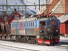 La photo représente une locomotive triple attelée à un convoi de minerai.