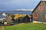 Kirkjubøur. Links Sint-Olafskerk uit de 12e eeuw. Het gebouw in het midden is Kirkjubøargarður (ook Roykstovan genoemd), 's werelds oudste nog bewoonde houten huis, tevens museum, uit de 11e eeuw. Op de achtergrond Sandoy en Hestur.