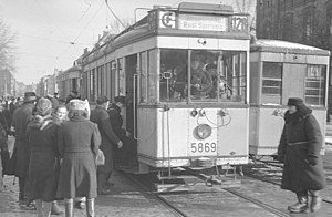 Tw 5869 (T 24) auf der Linie 128E nach Reinickendorf, Sportplatz mit zwei­sprachigem Zielschild in kyrillischer und lateinischer Schrift, daneben in Gegen­richtung ein B 24 auf der Linie 141 Richtung Bahnhof Gesundbrunnen (1945/46).