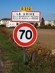 Semn de intrare în localitate pe D 312, specificând că aftul este împărțit între cele două orașe.  Viteza limitată la 70 km / h.
