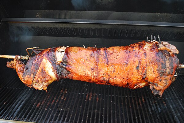 A pig being slow-roasted on a rotisserie