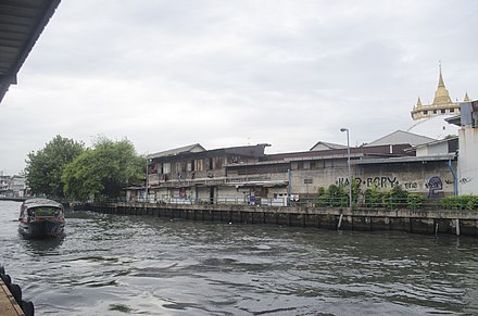 A boat approaches the Panfa Leelard Pier with Golden Mount Temple on the right corner