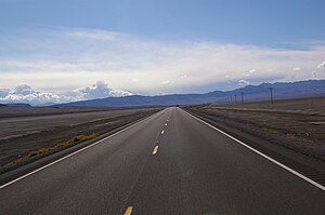 Long, straight desert highway stretching to the horizon.