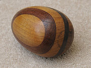 A brown and tan wooden egg that is round and used for mending clothes