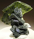 Green titanite crystal perched right at the top of a column of gray, chlorite-included crystals