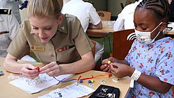 US Navy 100901-N-6220J-045 Yeoman 3rd Class Erin Anderson, assigned to Navy Operational Support Center, Akron, helps a patient at the Rainbow Babies ^ Children's Hospital assemble a necklace.jpg