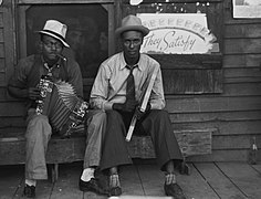 Zydeco players in 1938 playing accordion and washboard in front of store in New Iberia, Louisiana