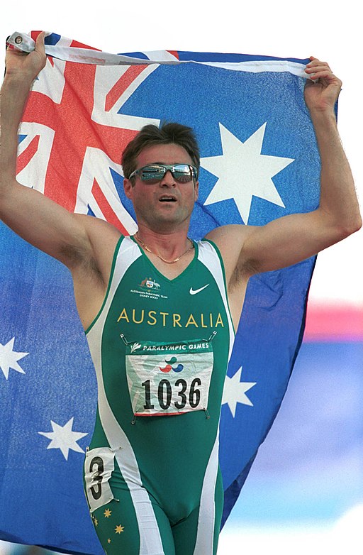 141100 - Athletics track Neil Fuller Australian flag - 3b - 2000 Sydney race photo