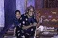 A smiling textile worker with a child, a spindle and wool combs, where?