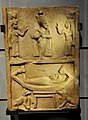 A mummy rests on a sacred boat guarded by Anubis. Above, figures of Osiris, Isis, and Nephthys. Sandstone stela. From Egypt, 332 BCE to 395 CE. Kelvingrove Art Gallery and Museum, Glasgow, UK.jpg
