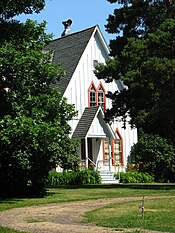 Photograph of a house with a high, steep roof and peaked windows