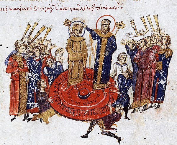 Anachronistic depiction of a coronation by being raised on a shield, from the Madrid Skylitzes. The crowned figure is meant to be Michael I Rhangabe, although there is some debate concerning the identity of the two figures, as the scene appears to be drawn from a lost original source. It has been proposed that the image depicts the coronation of a co-emperor (left) by a senior emperor (right).[48]