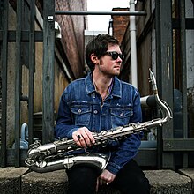 a young man posing with a saxaphone