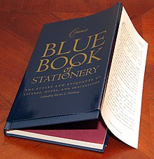 Photographie d'un livre recouvert d'une jaquette partiellement dépliée. Le livre est intitulé Blue Book of Stationary.