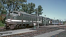 A battered Penn Central EMD E8 leads another E8 and two coaches at Albany-Rensselaer in 1969