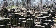 Remains of the Woodland Avenue gatehouse, loosely piled in the northeast quadrant of Woodland Cemetery in 2017. Gatehouse stones 10 - Woodland Cemetery.jpg