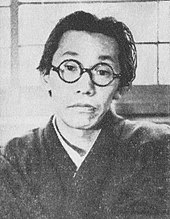 Photographie en noir et blanc d’un jeune homme japonais avec des lunettes et habillé en kimono.