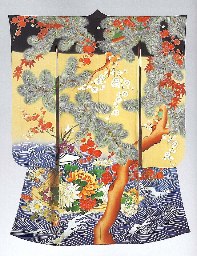 The back view of a long sleeved kimono decorated with a large tree and flowers on a black, yellow and wave-patterned background.