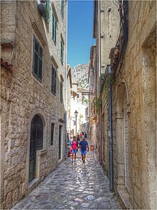 Narrow streets are a common feature in walking cities, where space is at a premium. People walking in Kotor.jpg