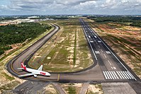 View of runway 11 with TAM Airlines Airbus A330-200 holding short. Manaus city center is at the background.