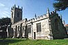 A stone church seen from the southeast, entirely battlemented, with pinnacles on the chancel and the tower