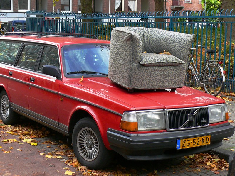 Street joke of the city Amsterdam - a red Volvo car with on its long nose a worn armchair. It was in the neighbourhood Kinkerbuurt; free street photo Amsterdam, Fons Heijnsbroek Autumn 2008