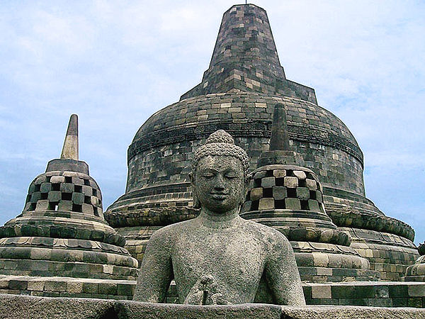 Buddha in an open stupa and the main stupa of Borobudur in the background.