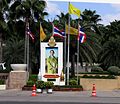 Kongens billede flankeret af såvel nationalflag, som det gule kongeflag. Hver dag har if. thai-tradion sin egen farve, gul er farven for mandag, kongen blev født en mandag.