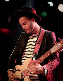 Gambar dari George "Twin Shadow" Lewis Jr., seorang pria berusia akhir 20-an. Dia memainkan gitar.