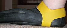 A fin grip positioned to secure a full-foot fin on the foot Yellow fin grip retaining a Technisub Ala swimming fin on the foot.jpg