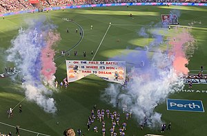 Western Bulldogs pemain berjalan melalui banner mereka.