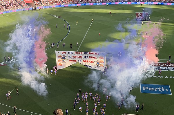 The Western Bulldogs players running through their banner. The last line reads: "Yield to none", which was the Bulldogs' finals slogan and an English translation of their club motto.