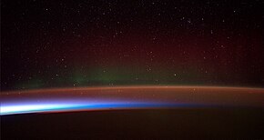 Airglow as pinkish orange sodium line at just below one hundred kilometers and a faint green line, at the edge of space and the lower edge of the thermosphere (invisible), sandwiched between green and red bands of aurorae streching over several hundred kilometers upward and the pink mesosphere, white and blue stratosphere, as well as orange troposphere afterglow and silhouettes of clouds at the bottom. Antarctic aurora ESA313457.jpg