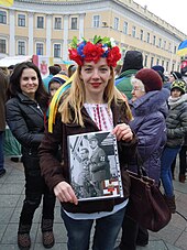 Protester against the Russian government holding an image portraying Dmitry Medvedev and Vladimir Putin as Nazis with a swastika made of colours of the Ribbon of Saint George and a Russian coat of arms in the centre, Odesa, 2014 Anti-War protest, Odessa 02.jpg