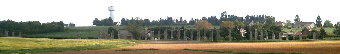 Vue d'une succession de piles et d'arches d'un aqueduc antique traversant un vallon.
