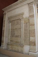 Reconstrucción del Arco de Augusto a tamaño real en el Museo de la Civilización Romana.  En las paredes de los pasillos laterales, las listas de los triunfalistas y cónsules de la República.