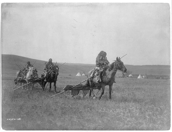 Gros Ventre moving camp on horses rigged with travois.