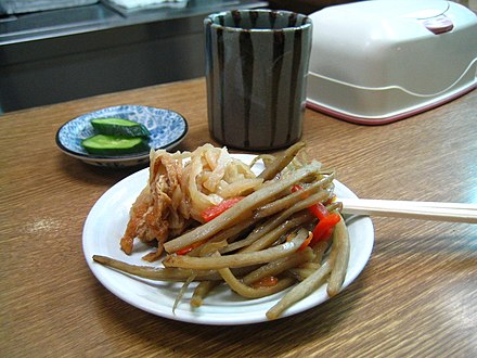 A dish containing a Japanese appetizer, kinpira gobō, consisting of sautéed burdock root and carrot, with a side of sautéed dried daikon