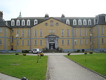 Large yellow three-storey building with tall narrow windows