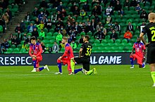 Players from FC Krasnodar and Chelsea F.C. kneeling at the start of a UEFA Champions League match in October 2020 FC Krasnodar vs Chelsea supporters 2020-10-31.jpg