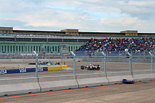 Scène de la course de Formule E de Berlin. Trois voitures sont dans un virage.