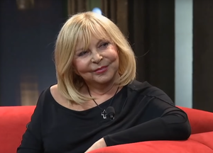 Hana Zagorová seated on a red couch, smiling and looking left of camera