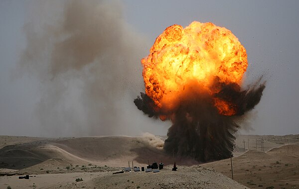 A controlled bomb disposal in Iraq, 2006; detonating the bomb causes fire and smoke to propel upward.