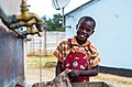 Garçonnet lavant son uniforme scolaire au robinet (Zimbabwe).