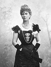 Thin Mary wearing a formal dress, a rope of pearls and a tiara