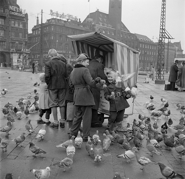 File:Mensen bij een kraampje waar duivenvoer wordt verkocht, op de voorgrond kinderen, Bestanddeelnr 252-8827.jpg