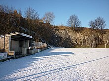 snow-covered football pitch with rock-faces behind