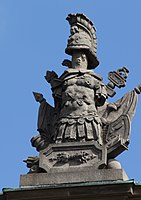42. Trophäe – Baumstamm, Helm, Schwerter, Harnisch, Liktorenbündel, Mörser, Lanzenfahnen, Kugeln, Relieftafel mit Blitzbündel des Jupiter.