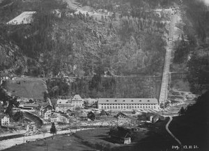 Centrála Amsteg I, nyní uzavřená, ve výstavbě v roce 1921. Nalevo rozváděč, napravo strojovna a trasa tlakového potrubí.  Nové sídlo Amsteg II je za starým ve vnitřku hory