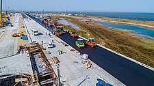 Asfaltado del tramo terminado del puente carretero del lado de Taman.  En el lado opuesto, se están realizando las obras de conexión de la rampa temporal con el puente.